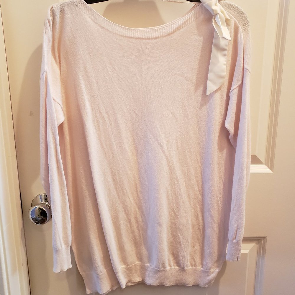 Pastel pink sweater with a cream satin bow on the shoulder